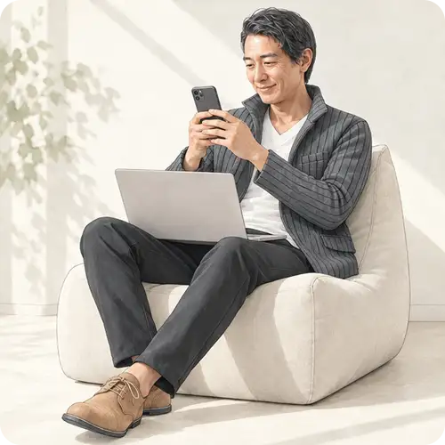 ソファでノートパソコンを膝に置き、落ち着いた表情で遠くを見つめる男性。Search Consoleの生成AIレポートで今後を見据えるイメージ。