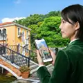 街並みでスマートフォンを使う女性｜AIに選ばれるホームページリニューアルのご案内