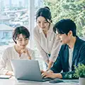 オフィスでノートPCを囲んで相談する3人｜世田谷区・東京のホームページ制作会社のご案内